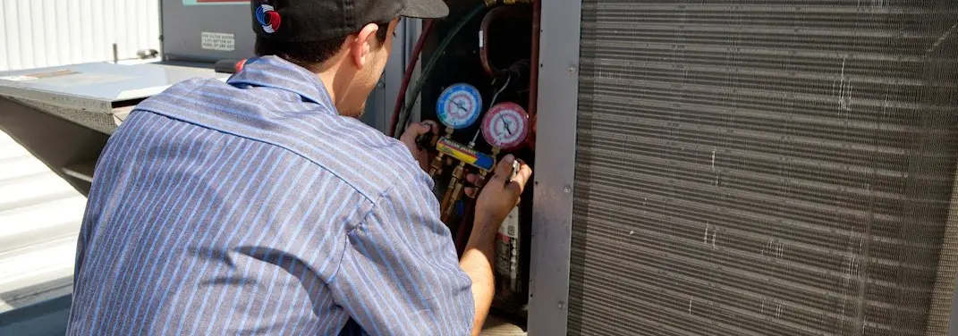 HVAC technician servicing a condenser unit in Hopkinton